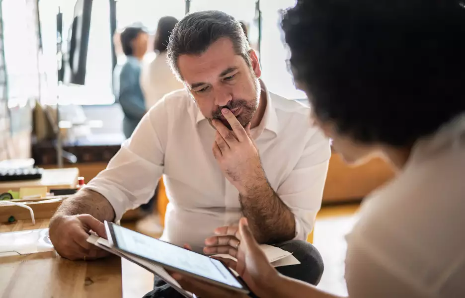 Un homme et une femme qui regardent et analysent les données techniques sur une tablette