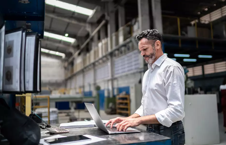 Un homme dans un hangar qui travaille sur son portable